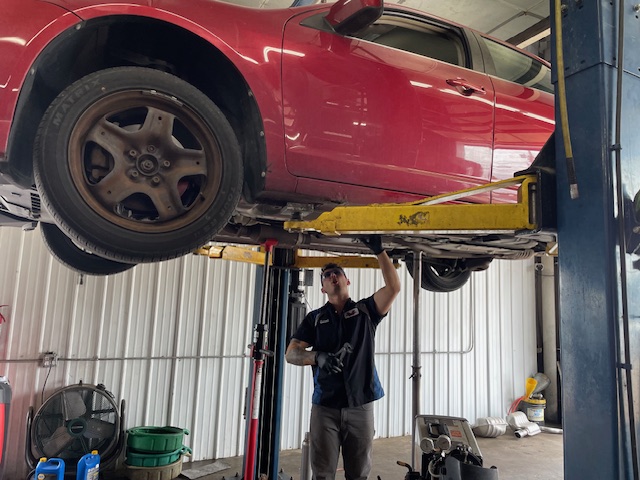 Red coupe raised on the two-post lift inside the Dartt Automotive bay